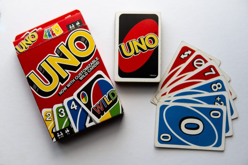 Box of Uno cards and its deck next to it, some cards sprawled into a fan