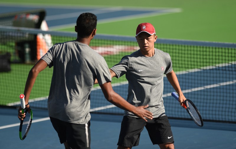 Two tennis players high five on the court during a game.