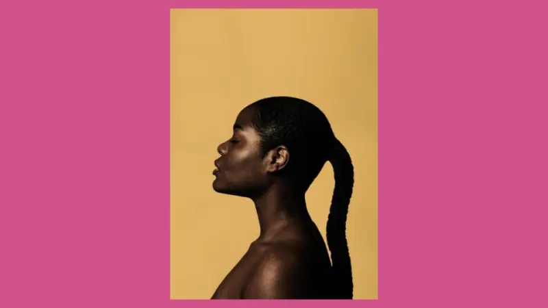 A Black woman in front of a yellow wall, posing for a pictorial photoshoot.