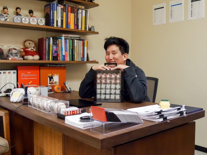 Gene Kim sits at desk holding box of poker chips