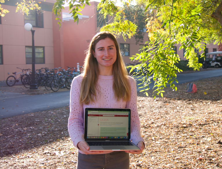 Meg Reinstra holding a computer with the website "Carta" on screen.