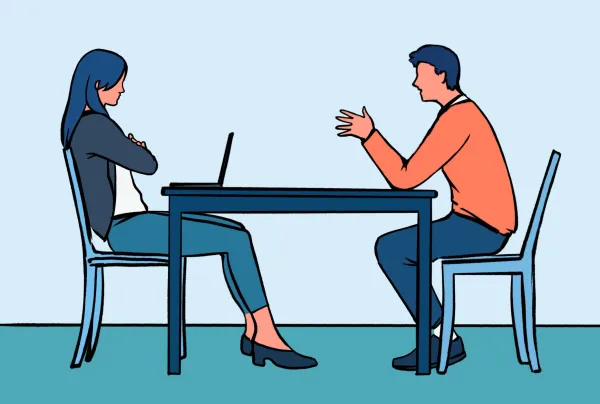 An interview for a pre-professional club: two people sitting across a table, talking, while one looks at their laptop.