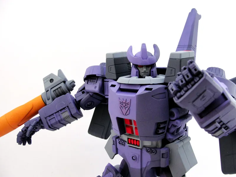 Toy robot of transformer Megatron, who is purple and is facing toward the audience, the weapon on his wrist pointing left.