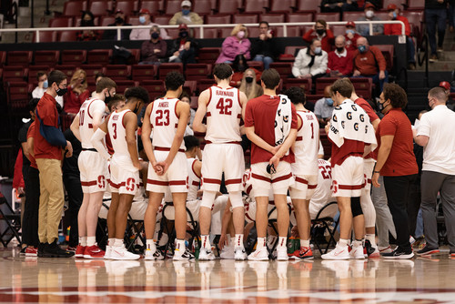 A group of basketball players huddled in a circle talking to the coach.