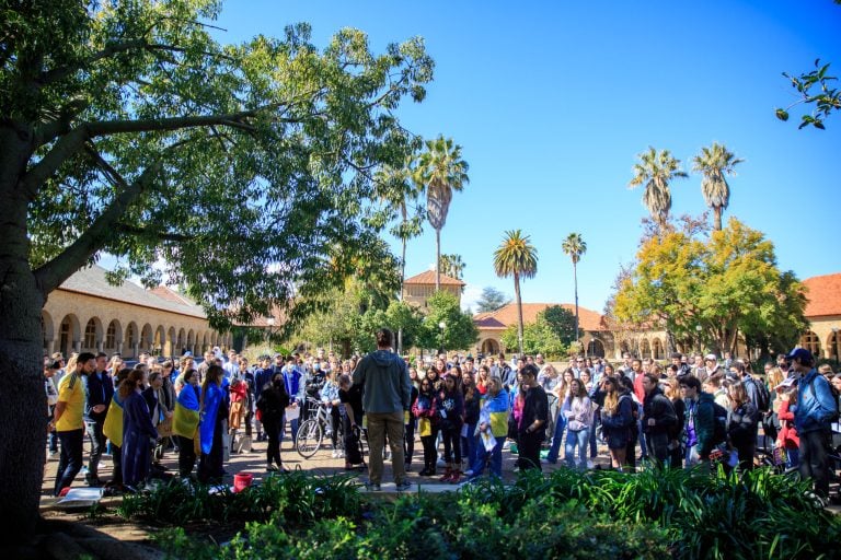 Speaker stands in front of crowd on main quad