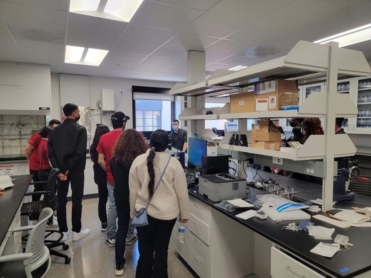 Several people stand facing away from the camera in a lab