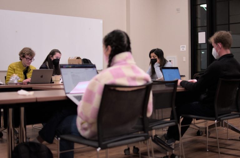 Five members of Graduate Student Council sitting around a table and looking at laptops.