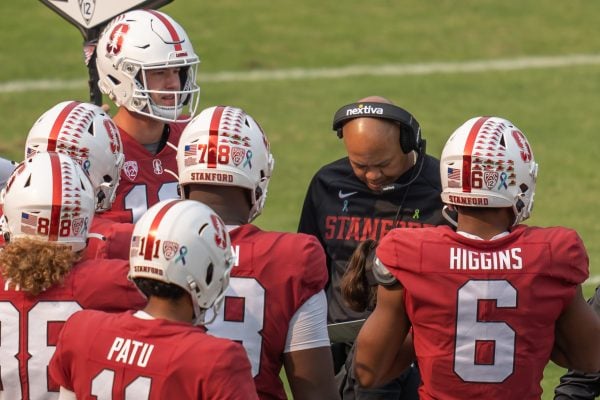 David Shaw huddles with several football players during a game.