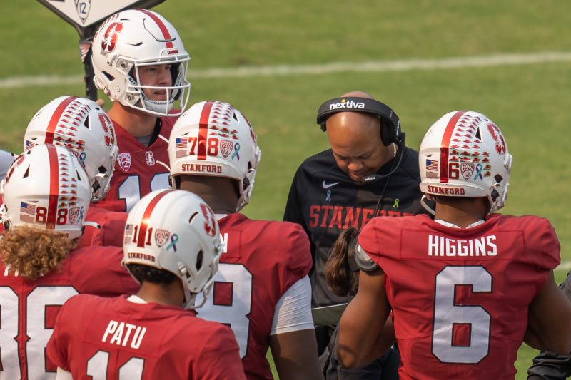 David Shaw huddles with several football players during a game.