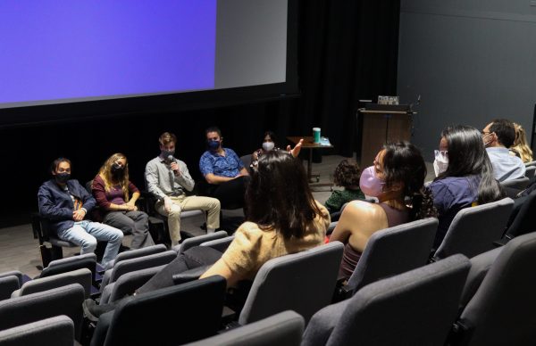 Five student panelists speak to a crowd in a small movie theater