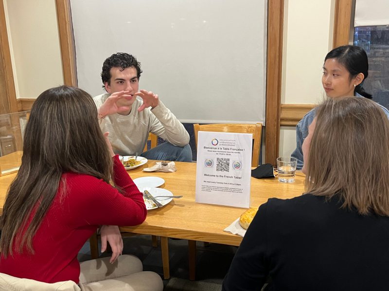 Four students sit around a table and talk to one another