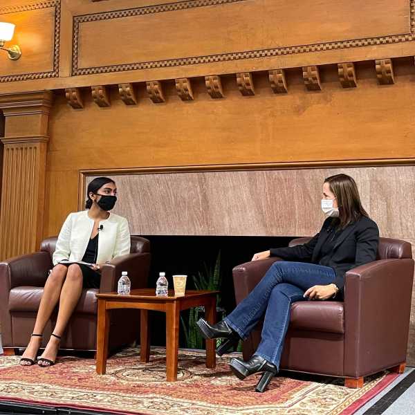 Stanford Women in Politics President Manasa Kumarrappan '23 sits in a brown chair across from California Lietuenant Governor Eleni Kounalakis at an in-person speaker event