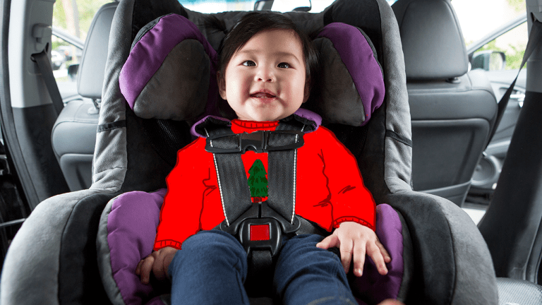 An infant in a Stanford tree shirt in a booster seat in a car