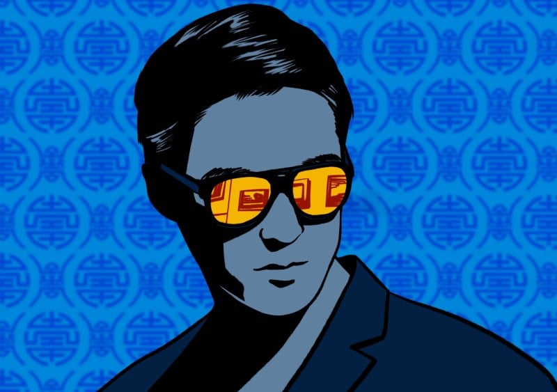 Man with dark hair wearing glasses against blue patterned background