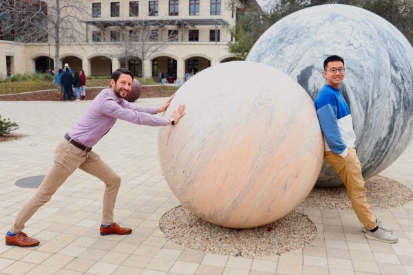 Professor Matteo Cargnello (left) pushes the globes in Engineering Quad as Ph.D. student Chengshuang Zhou (right) leans on them.