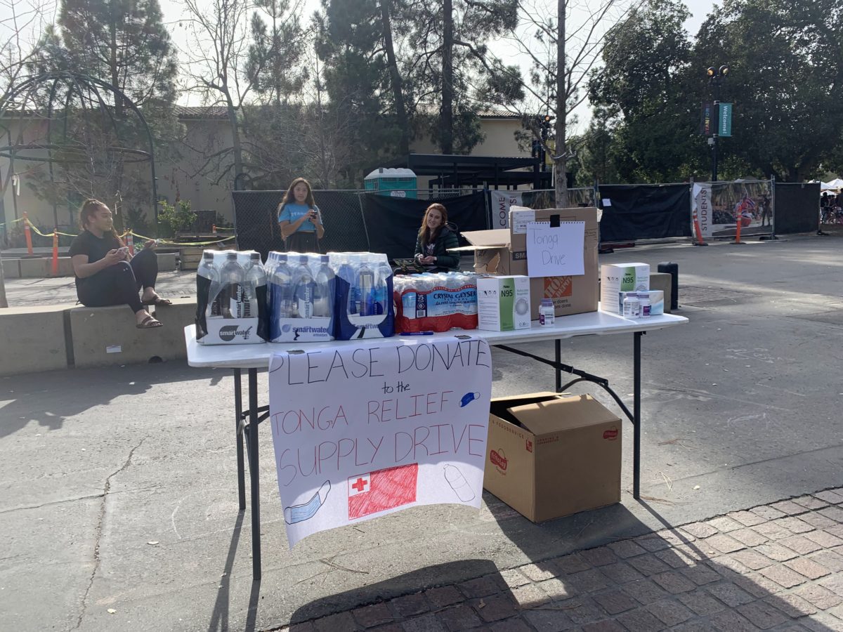 Table on White Plaza with bottles of water and "Please Donate to the Tonga Relief Supply Drive" signs