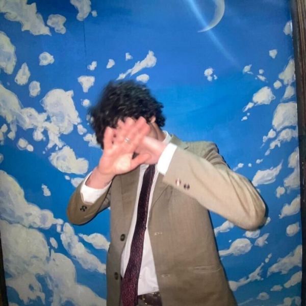 Student Artist Reid Devereaux covering his face with a background of fake clouds