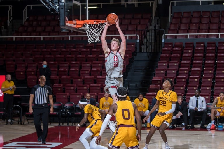 James Keefe reaches the ball up to the basket with several defenders around him.