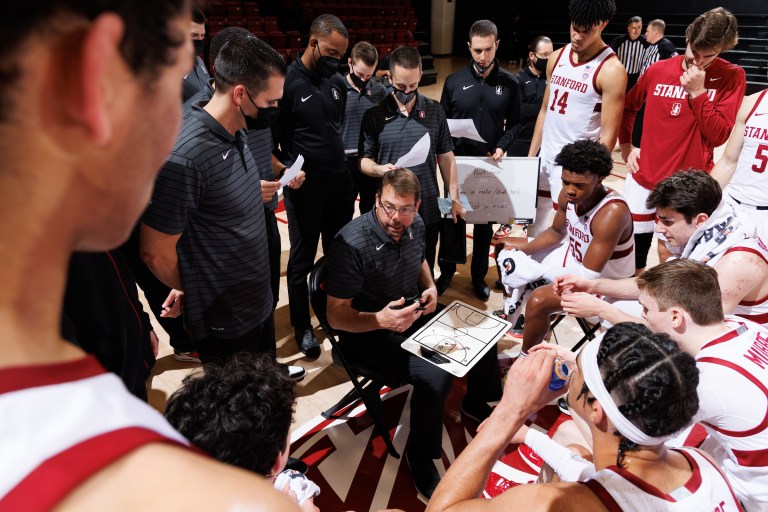 Jerod Haase speaks to the men's basketball team as the players huddle around him.