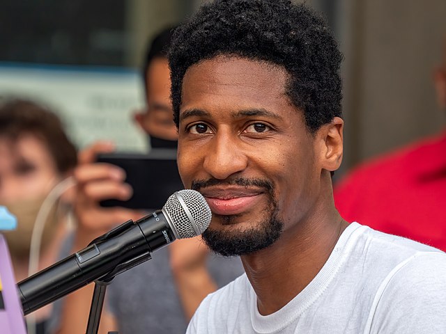 A close up of Batiste smiling into a microphone.