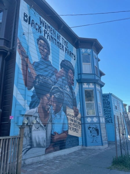 A tall mural stands on the side of a building in San Francisco portraying four Black women. Text reads "Women of The Black Panther Party."