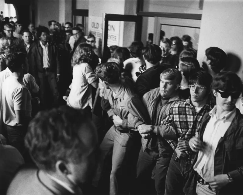Black and white photo of students linking arms in front of Old Union, protesting the Vietnam War