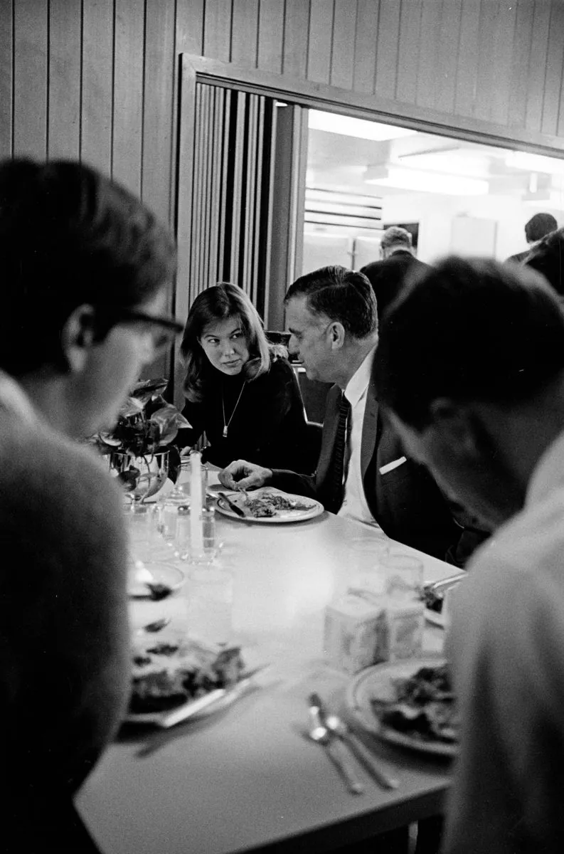 A young woman looks at an older man at a dinner table.