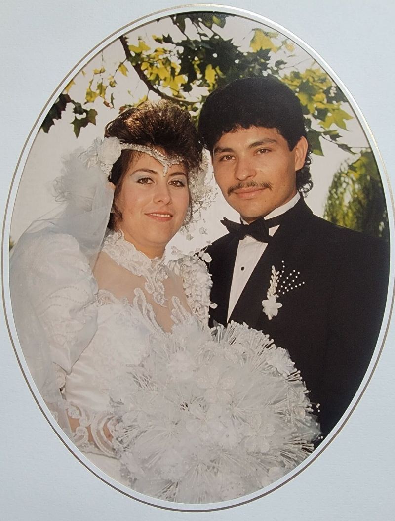 A woman in a wedding dress and a man in a suit smile at the camera.