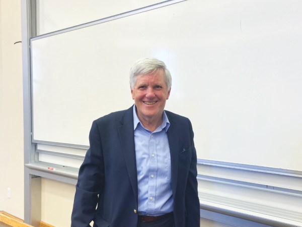 David Hayes standing in front of a white board and wearing dark blue suit.
