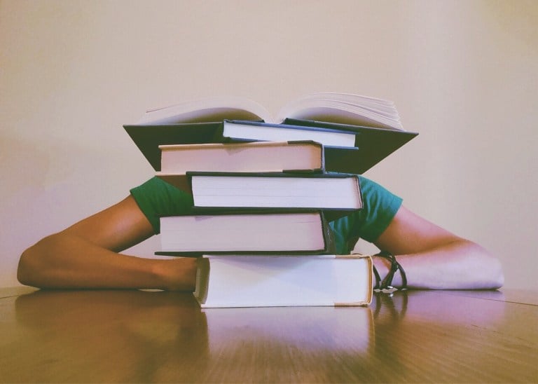 A student buried behind a stack of books.