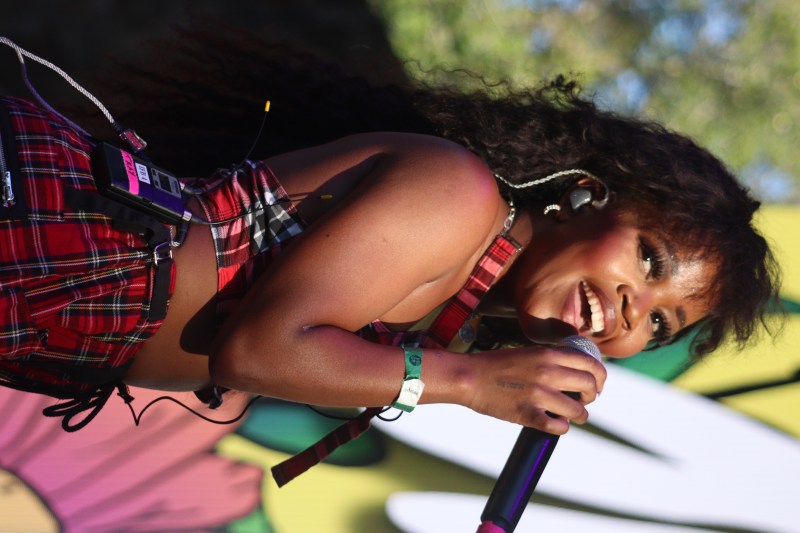 tkay maidza singing with a smile on her face wearing red plaid outfit, holding microphone on stage