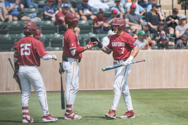 Several Stanford baseball teammates high five each other during a stoppage in play.
