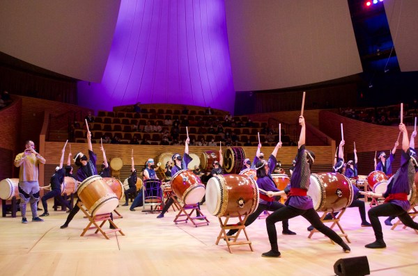Stanford Taiko performers pointing their sticks to the sky while performing at Bing Concert Hall