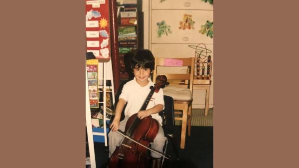 Author, as a child, sitting in a chair and posing with his cello.