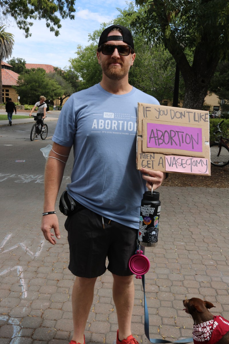 Ryan Miller, Marine Corps veteran, stands in front of Stanford Bookstore. He holds a sign that reads "If you don't like abortion, then get a vasectomy." 