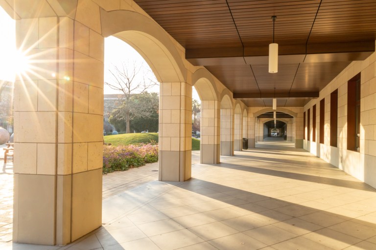 The sun shines into an outdoor hallway.