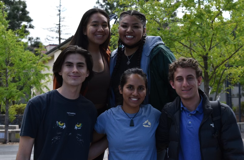 A group of five students smile at the camera. 