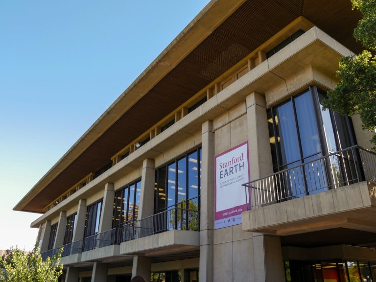 a two story windowed building with a banner reading 'Stanford Earth' and several second story balconies