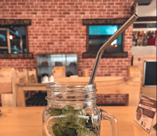 the top of a glass handled mason jar containing lemon water with a bent metal straw sticking out