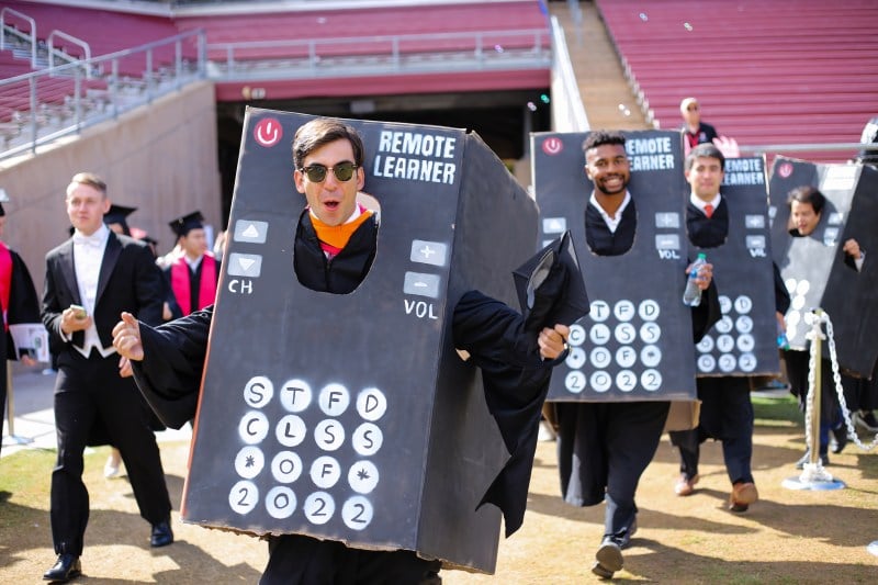 Four men in a row wearing cardboard cutouts of a "remote", with words "Remote learner" written on the top