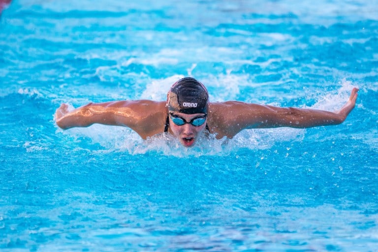 Torri Huske mid-stroke, with her arms outstretched and upper body out of the water, during a relay event.