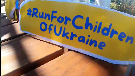 A yellow sign that reads "#RunForChildrenofUkraine" in blue text