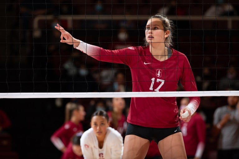 Sami Francis stands at the net and signals to her teammates.