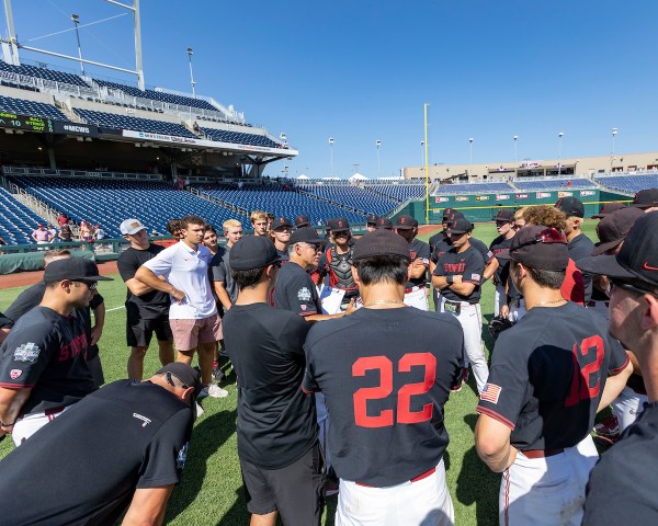 Stanford baseball huddles together on the field.