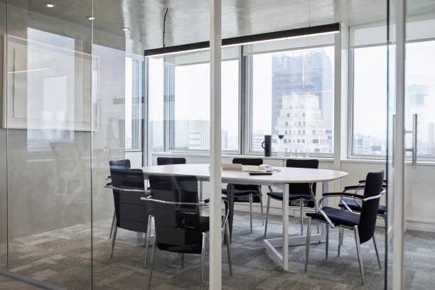Meeting room with glass walls, containing a round table surrounded by empty chairs.