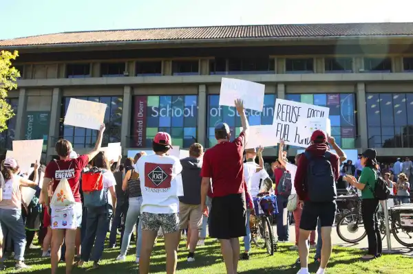 Protestors hold up signs facing Stanfords Doerr School of Sustainability