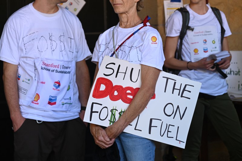A protester holds a sign that reads "Shut the Doerr on Fossil Fuel"