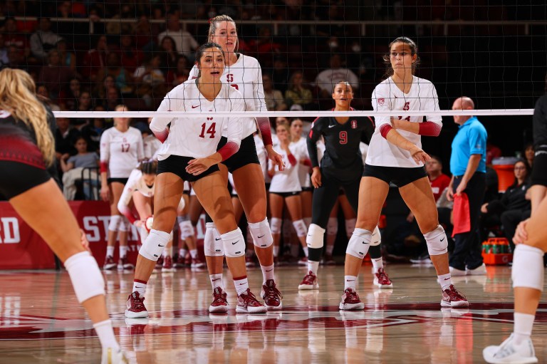 McKenna Vicini, Kendall Kipp and Elia Rubin stand at the net during a volleyball game.