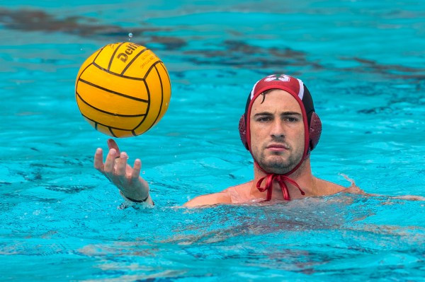 A water polo player in the water holding a water polo ball.