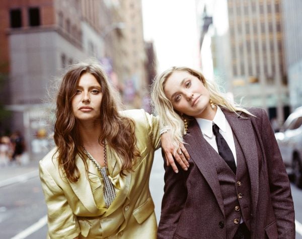Alyson Michalka, left, and Amanda Joy Michalka, right, stand with neutral expressions in the middle of a city street